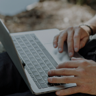 Mãos digitando em um notebook, representando a personalização e adaptação do PostgreSQL às necessidades do usuário.